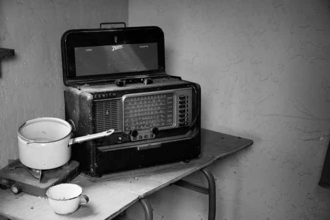 grayscale photo of vintage radio beside stove with cooking pot